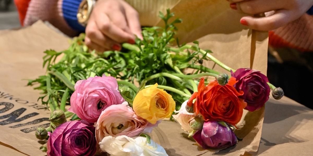 Person in jumper wrapping flowers in brown paper